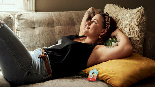 A woman relaxes on a couch with her vape by her side